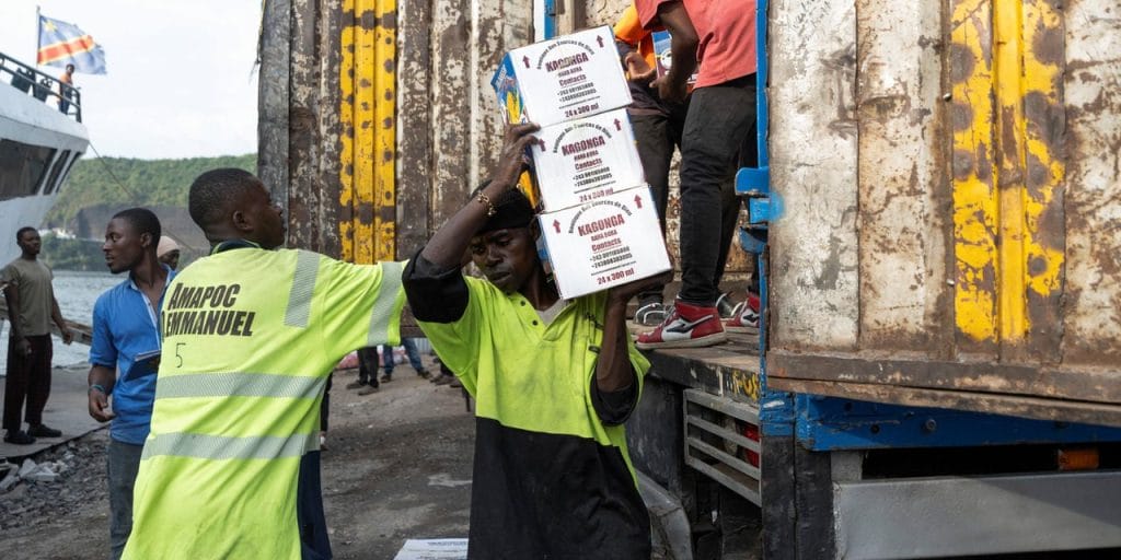 Baggage handlers work to load goods onto the Emmanuel boat after its first trip between Bukavu and Goma since the city was taken over by M23 rebels, showing DRC Drops Tax Plan on M23-Held Areas After Public Backlash